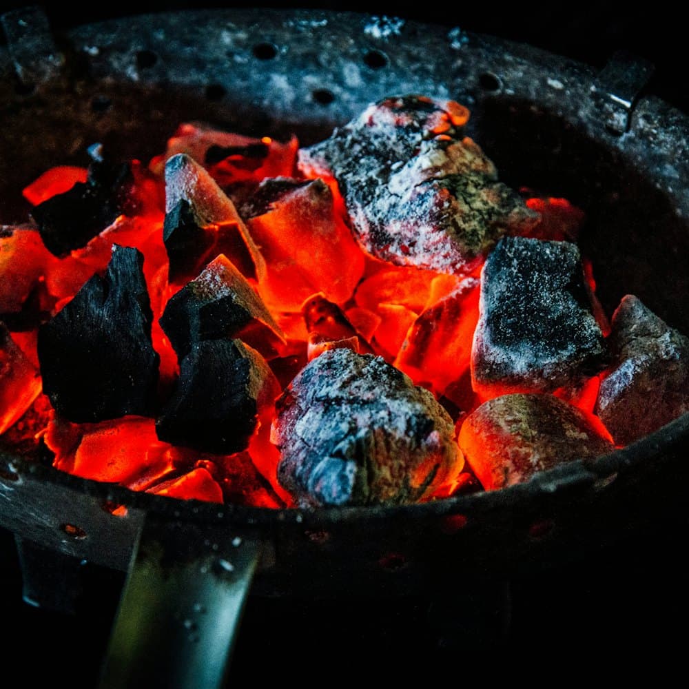Lumps of charcoal glowing red in a clay brazier