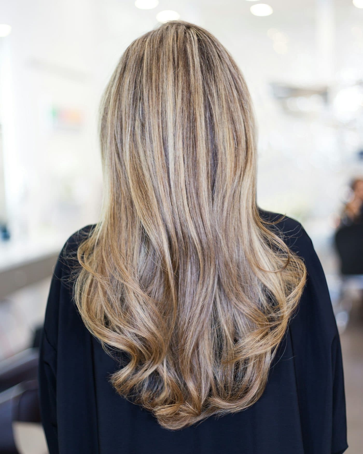 Long hair seen from behind, dark blonde at the roots melting into pale, loosely curled ends