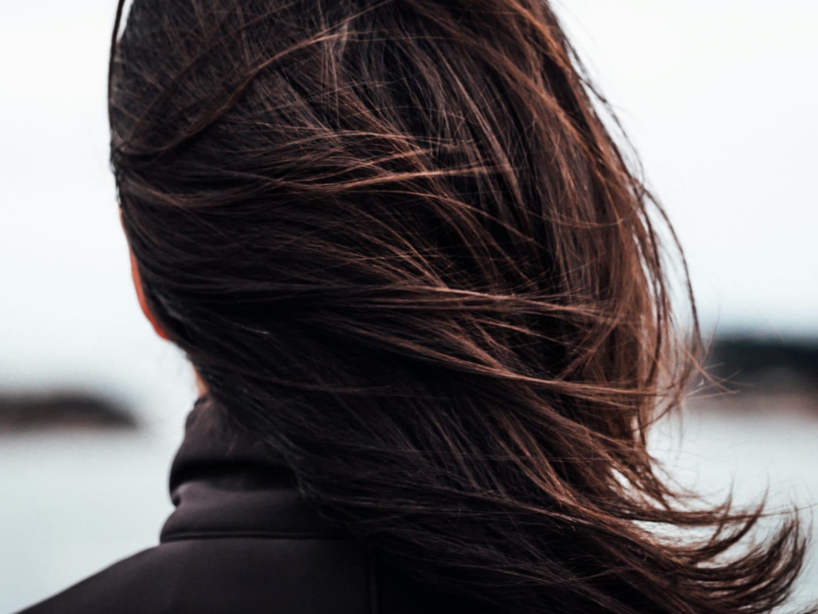 Dark brown layered hair caught mid-movement, seen from behind