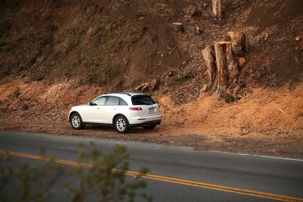 White SUV pulled over beside a road cut into red earth